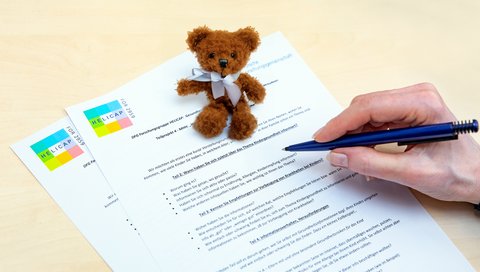 A little brown teddy bear sits on a questionnaire.