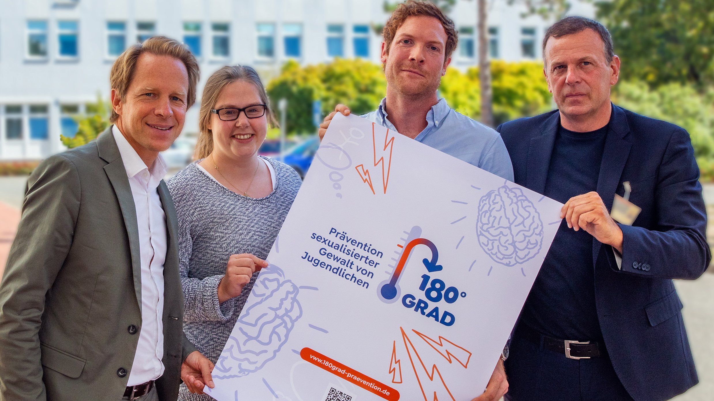 Professor Dr. Tillmann Krüger, Theresa Engelmann, Dr. Jonas Kneer und Klinikdirektor Professor Dr. Stefan Bleich schauen sich das Werbe-Poster zur neuen Ambulanz „180Grad“ an