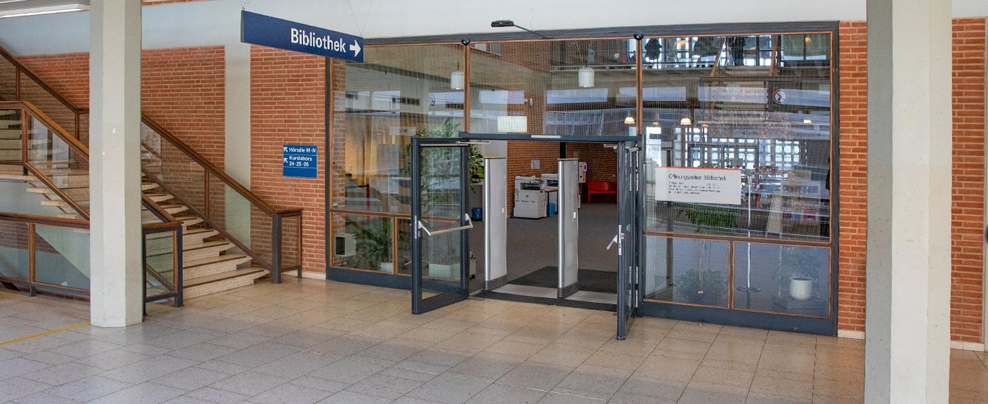 Der Eingangsbereich der Bibliothek mit geöffneten Türen und Blick ins Foyer durch die großen Glasscheiben