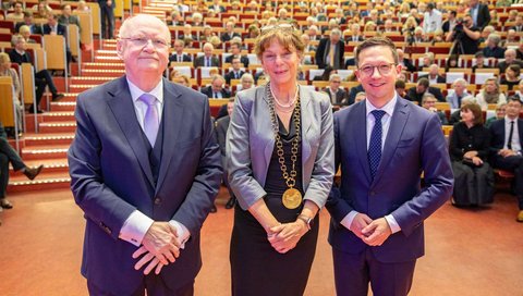 Denise Hilfiker-Kleiner in der Mitte mit Professor Manns und Falko Mohrs bei der Amtskettenübergabe im Hörsaal F