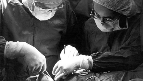 Ein Mann und eine Frau stehen nebeneinander in einem OP-Saal und operieren.