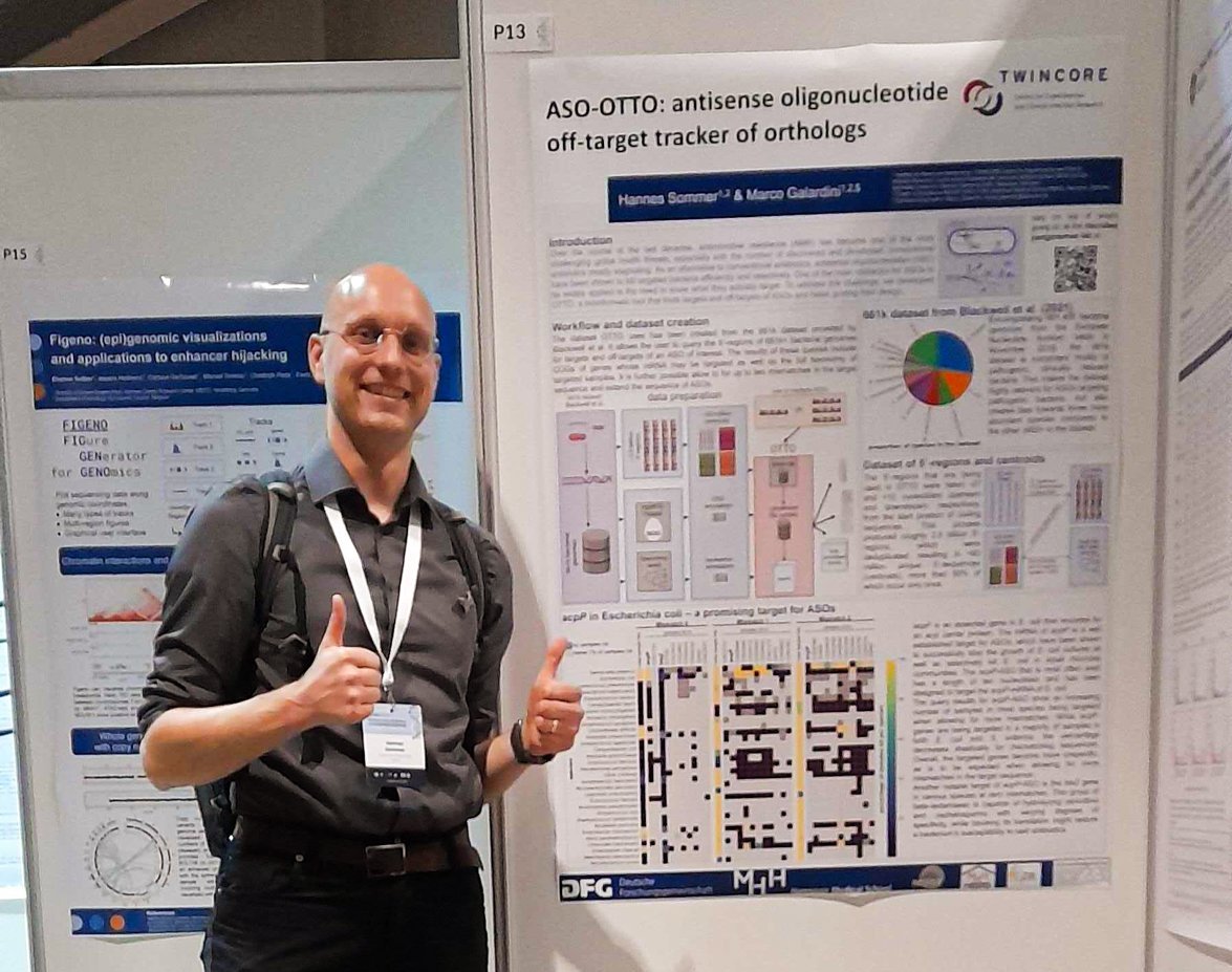 Der Doktorand Hannes Sommer steht vor seinem Poster über Antisense-Oligonukleotide (ASO).