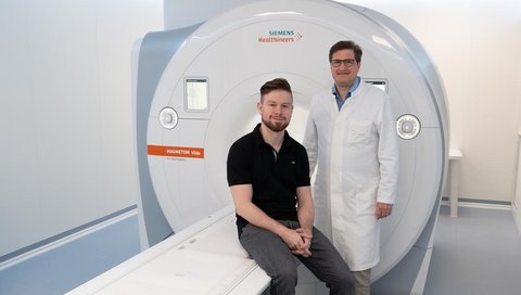 Dr. Andreas Voskrebenzev, physicist (left) and Professor Dr. Jens Vogel-Claussen (right), stand at an MRI scanner.