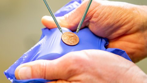 Winzige Instrumente eines mikrochirurgischen OP-Roboters umfassen eine 5-Cent-Münze. 