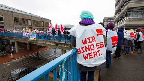 People with Verdi warning strike waistcoats stand in front of building I2 on the MHH campus.