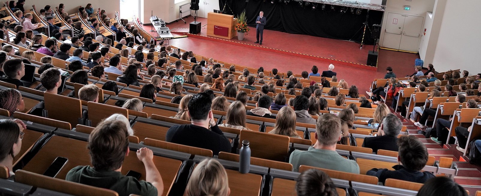 Blick von oben in den Hörsaal F der MHH. In den Reihen sitzen viele jungen Menschen, vorne am Pult steht eine Person.