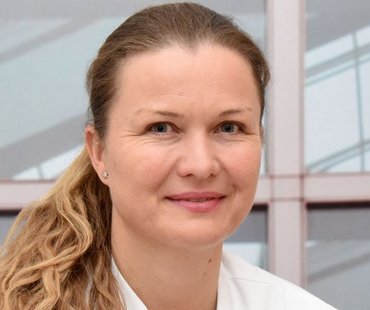 Porträtbild von Agnieszka Denecke, die einen weißen Arztkittel trägt. 