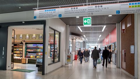 Blick in die Ladenpassage im zentralen MHH-Bettenhaus. Menschen laufen den Flur entlang, rechts und links sind Geschäfte. 