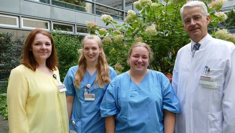 The two MFA trainees Victoria Minch (22) and Lilly Hoffmann (25) are standing next to each other, with MHH Vice President Frank Lammert and Miroslawa Kurt from the MFA training centre standing to their left and right.