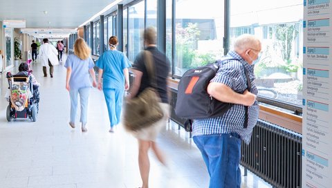 Several people walk across a corridor in the central ward block at MHH