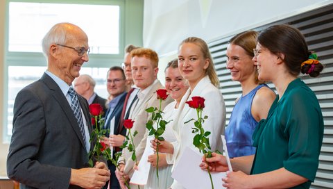 Professor Piepenbrock überreicht rote Rosen an die Absolvent:innen. 