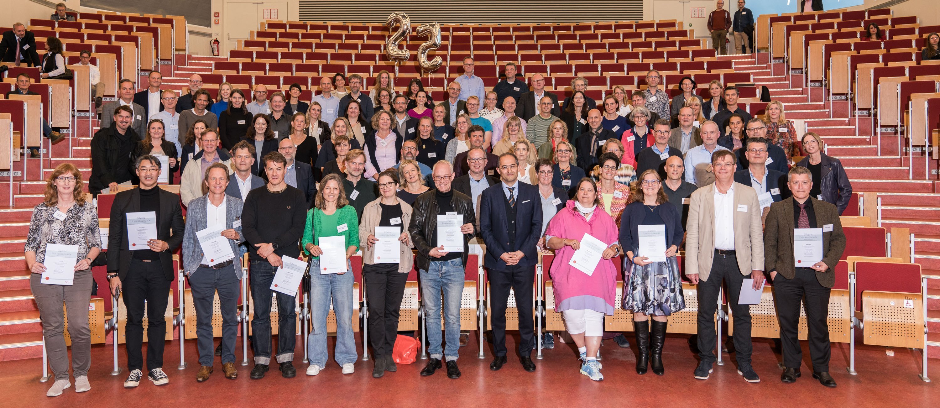 Die Jubilar:innen haben sich für das Foto in den ersten fünf Sitzreihen des Hörsaals aufgestellt.