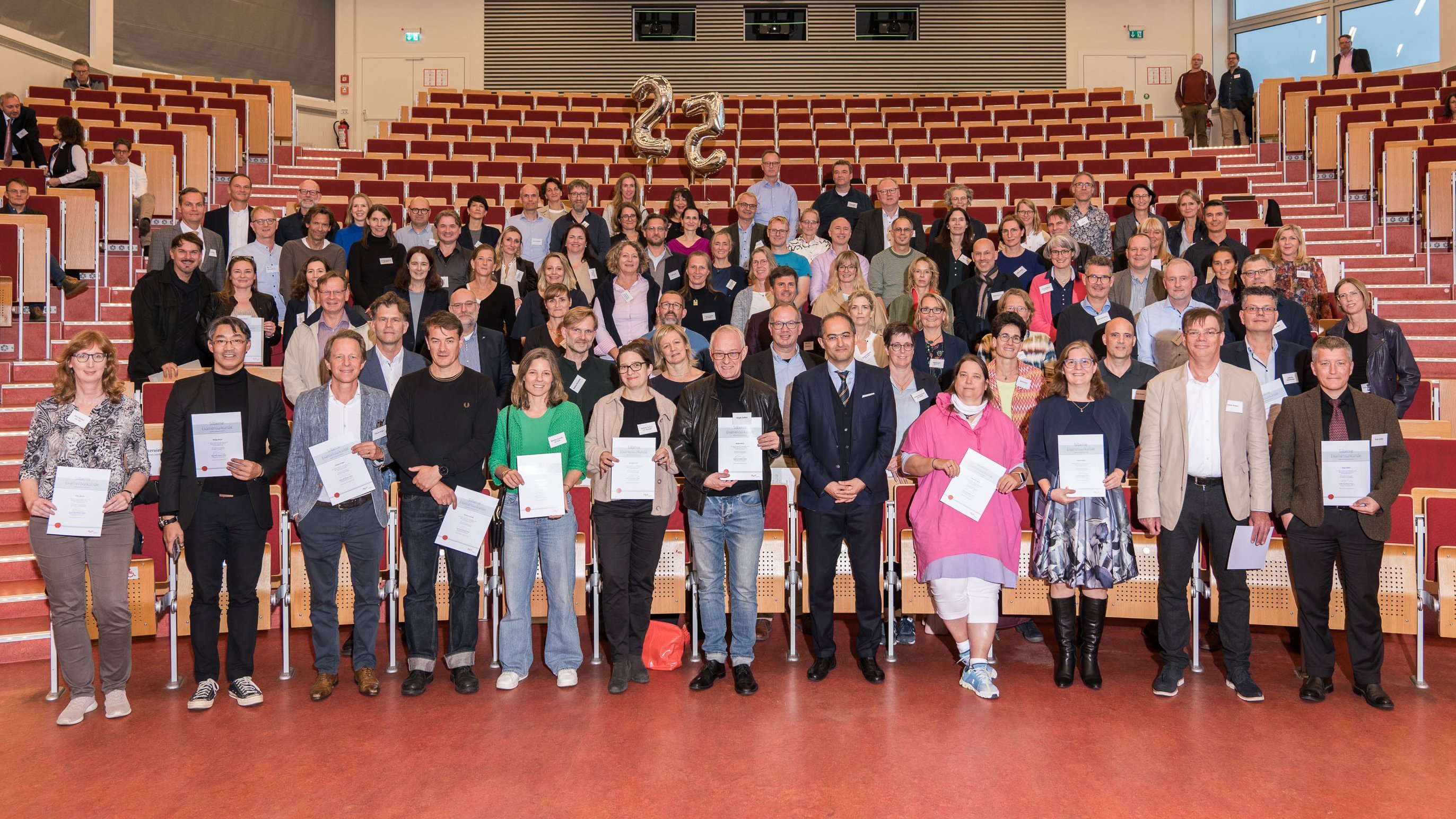 Die Jubilar:innen haben sich für das Foto in den ersten fünf Sitzreihen des Hörsaals aufgestellt.