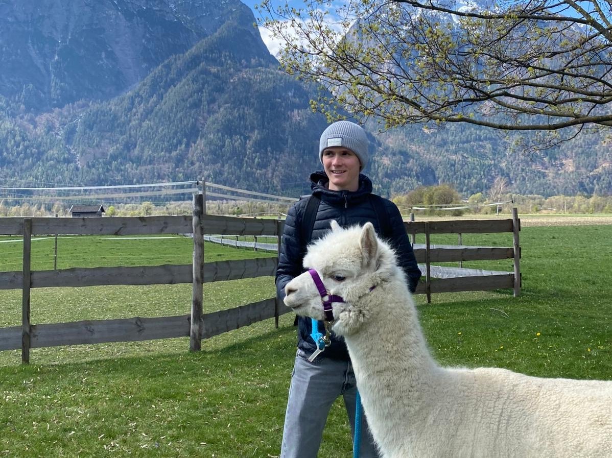 Copyright: Privat Junger Mann steht mit Alpaka auf einer Wiese.