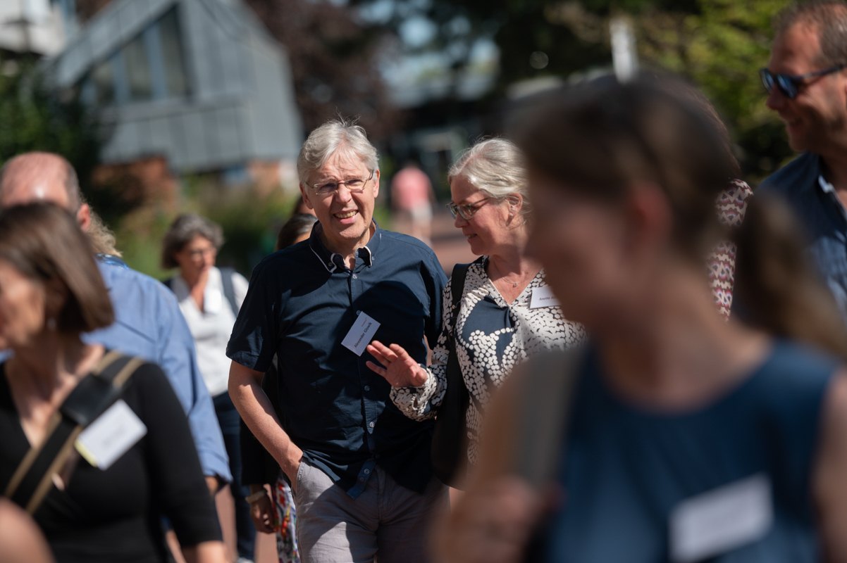 Absolvent:innen gehen in Gruppen über den Campus.