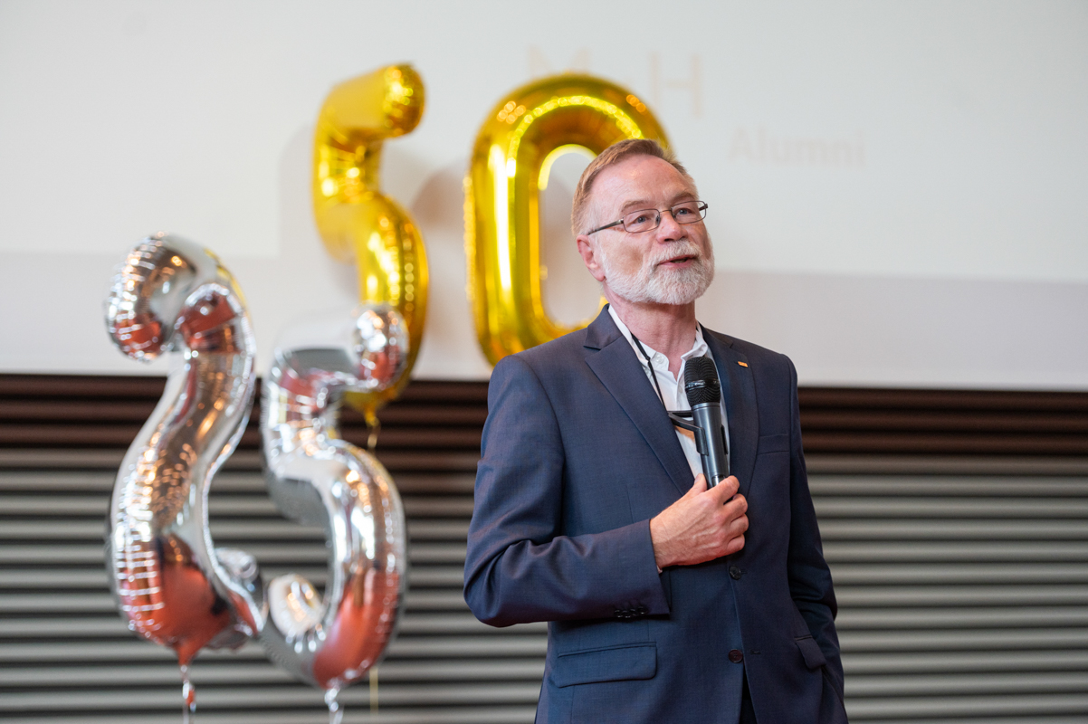 Professor Just spricht, im Hintergrund schweben heliumgefüllte Luftballons in Form einer 25 und einer 50.