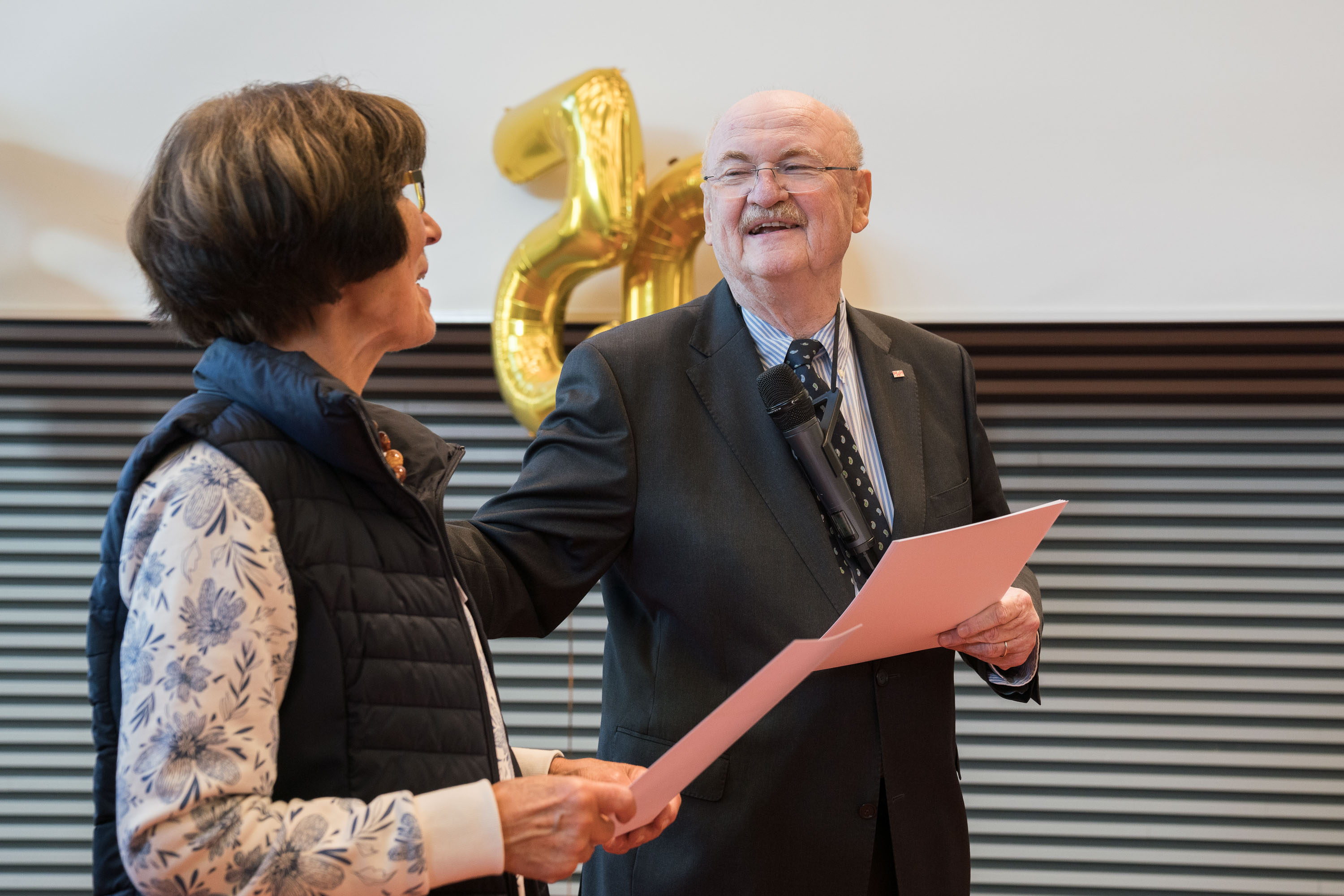 Professor Dr. Manns übergibt lächelnd eine Urkunde an eine Jubilarin.