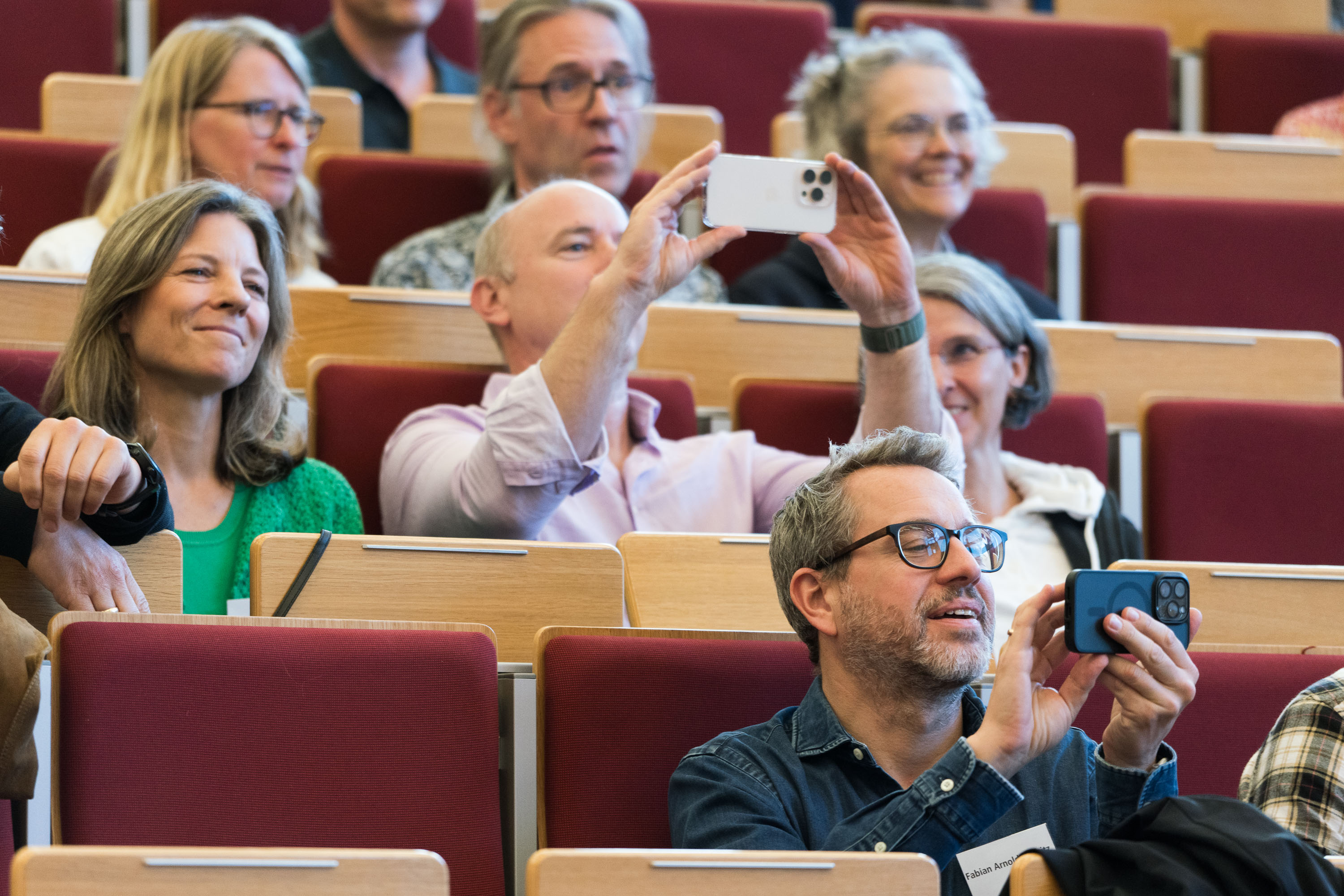 Die Ehemaligen fotografieren von ihren Sitzplätzen in Hörsaal F die Urkundenübergabe,