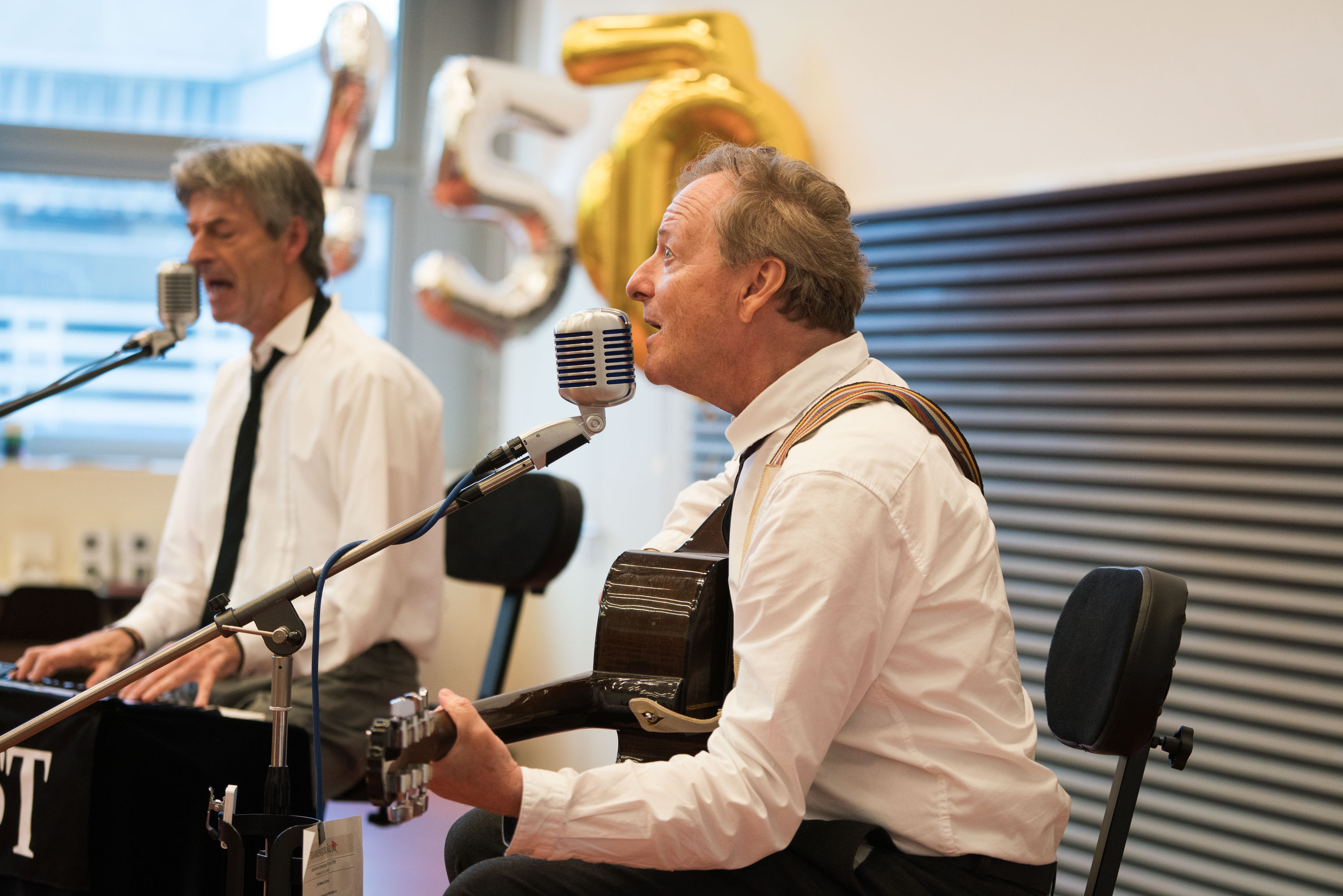 Zwei Musiker spielen Klavier und Gitarre und singen dazu.