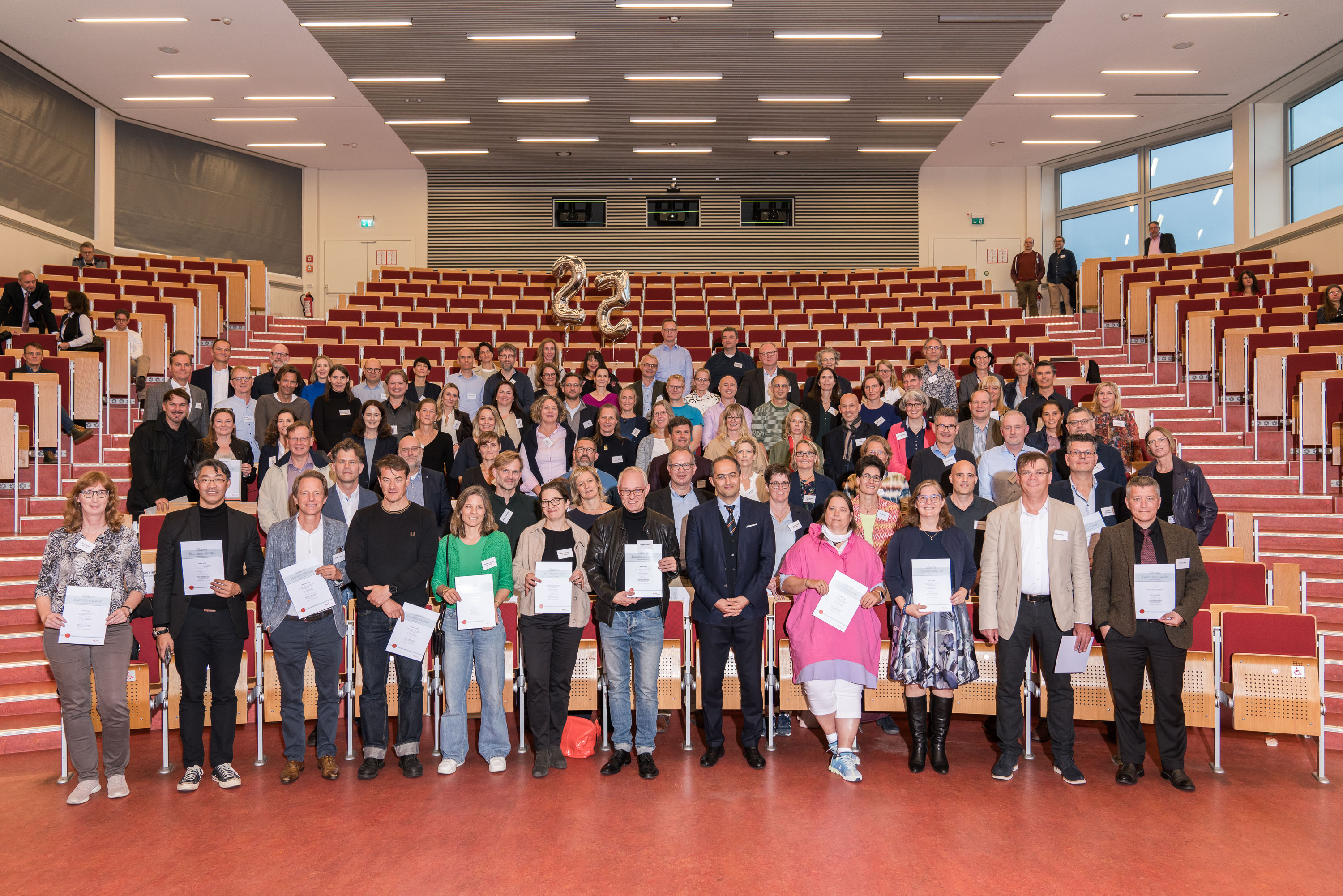 Die Jubilar:innen haben sich für das Foto in den ersten fünf Sitzreihen des Hörsaals aufgestellt.