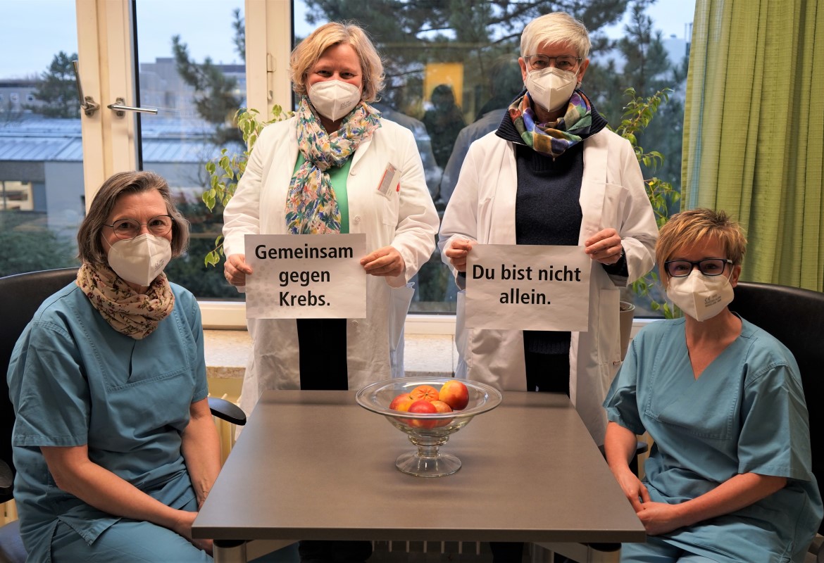 Vier Mitarbeiterinnen der Ernährungsberatung halten ein Schild hoch, auf dem steht "Gemeinsam gegen Krebs. Du bist nicht allein."