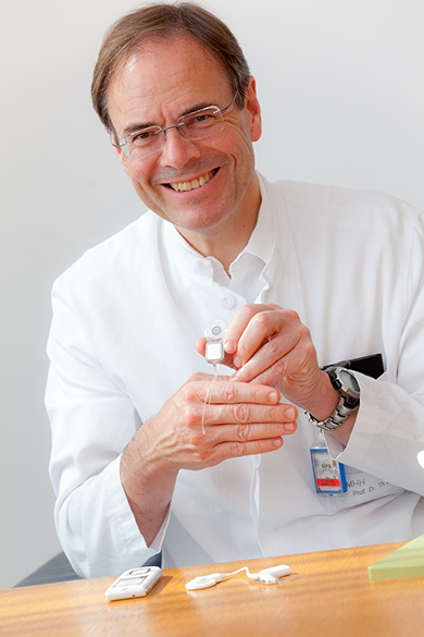 Klinikdirektor Prof. Lenarz im Portrait, präsentiert ein Cochlea-Implantat