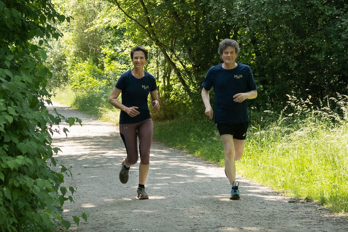 MHH-Vizepräsidentin Martina Saurin und Dr. Eckhard Schenke, Vorstand der Förderstiftung, joggen gemeinsam einen Waldweg entlang.