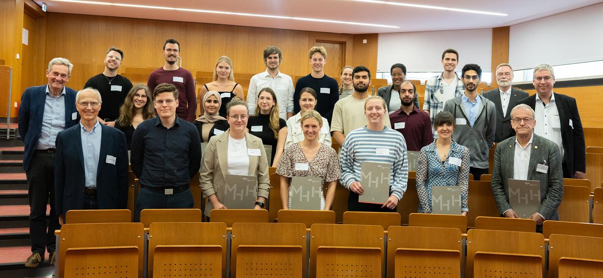 The German scholarship holders at Hannover Medical School (MHH) for the 2023/24 academic year stand together with their sponsors in a lecture theatre for a group photo. 