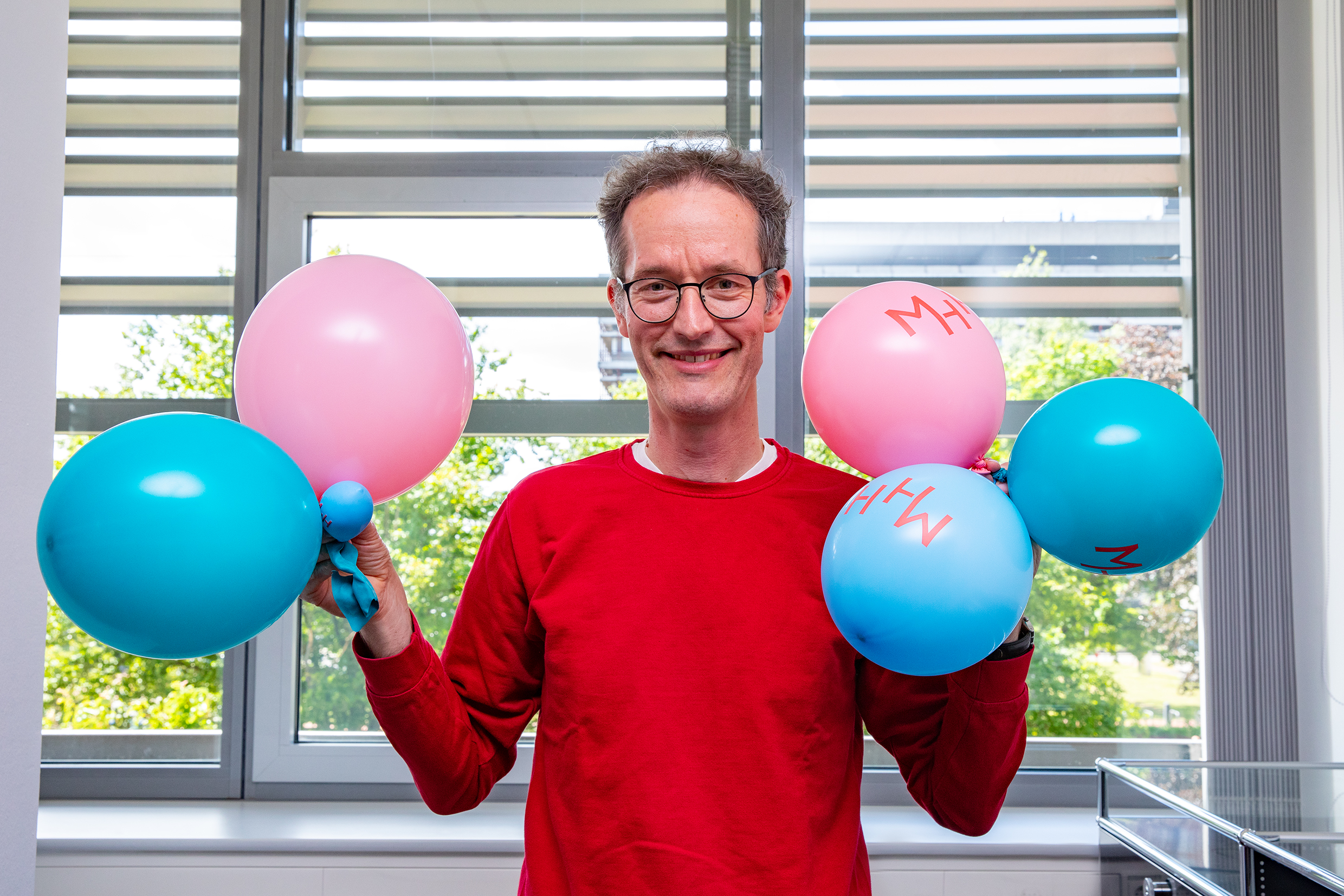 A man holds balloons in both hands.