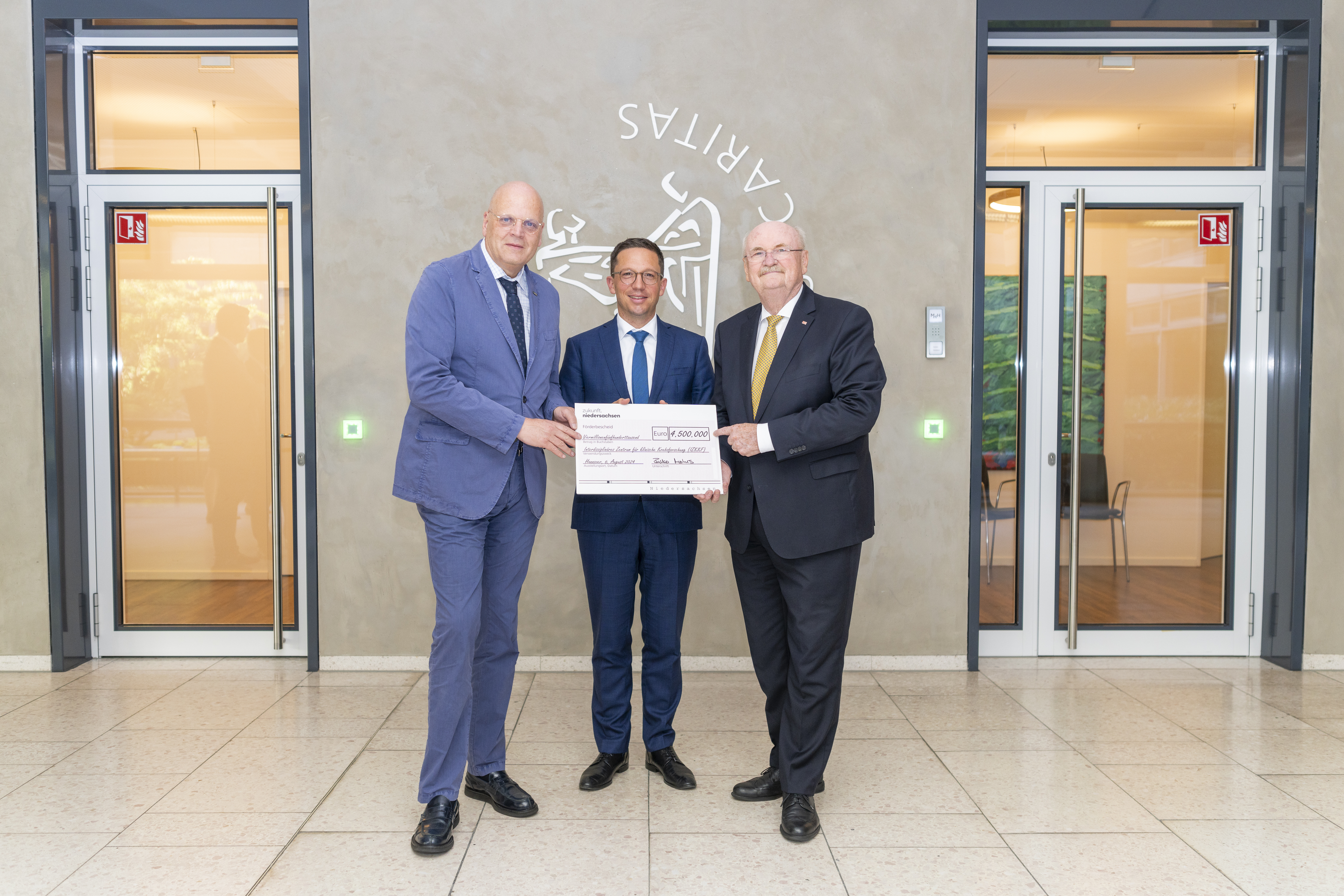 Minister Falko Mohrs (centre) hands over the funding decision to Professor Michael Manns (right) and Professor Wolfgang Brück.