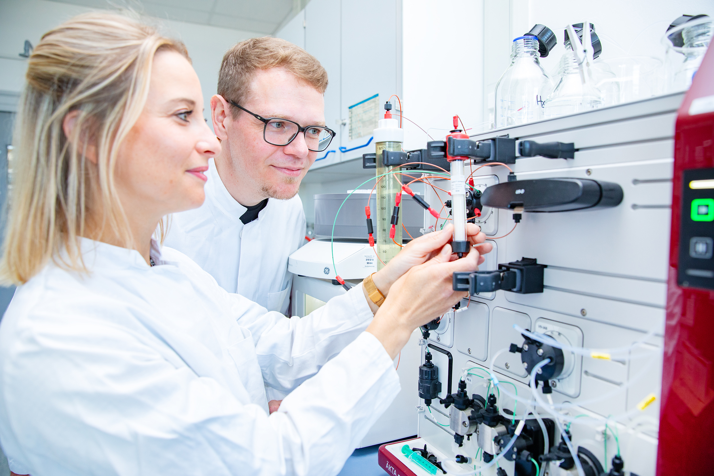 A man and a woman are standing in front of a chromatograph.