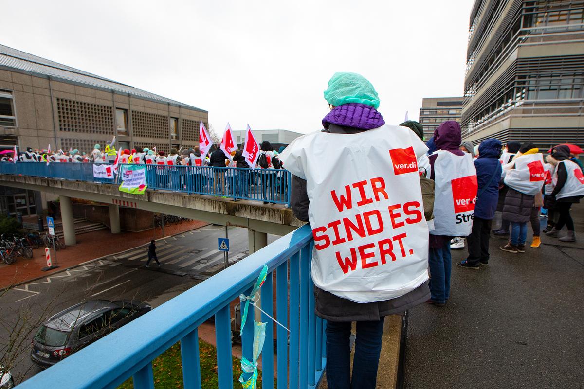 Menschen mit Verdi-Warnstreik-Westen stehen vor dem Gebäude I2 des MHH-Campus.