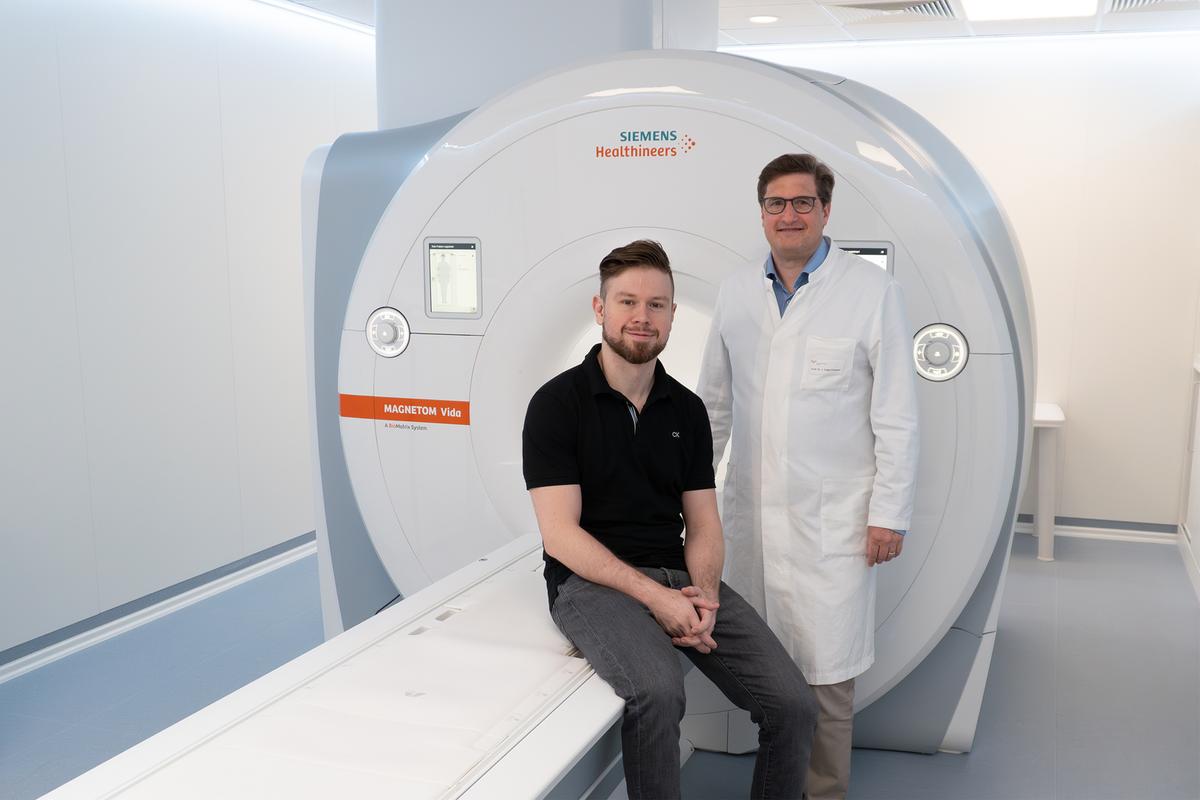 Dr. Andreas Voskrebenzev, physicist (left) and Professor Dr. Jens Vogel-Claussen (right), stand at an MRI scanner.