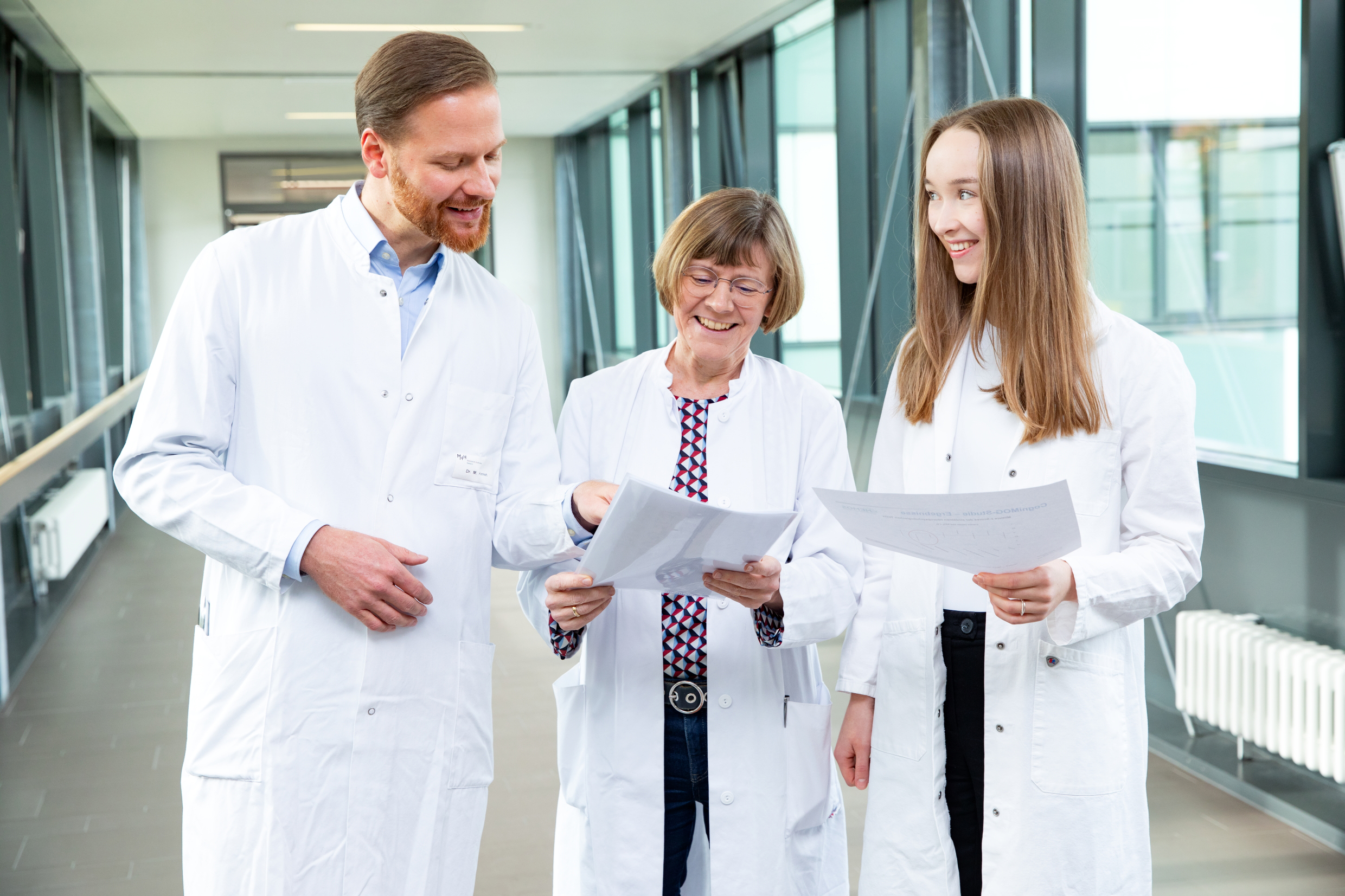 A doctor and two female doctors in white coats are standing next to each other.