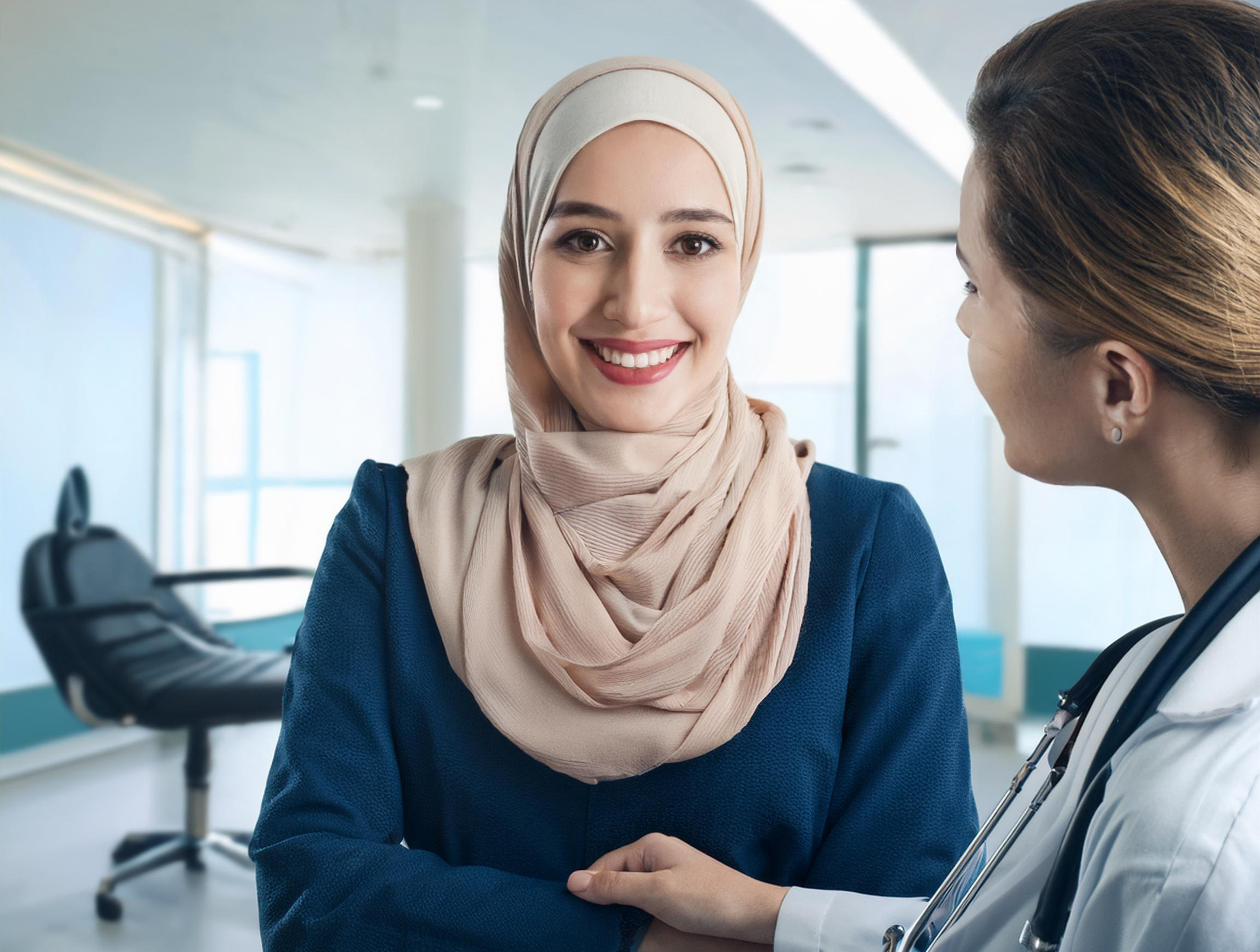 A woman wearing a headscarf stands next to a woman in a white coat.