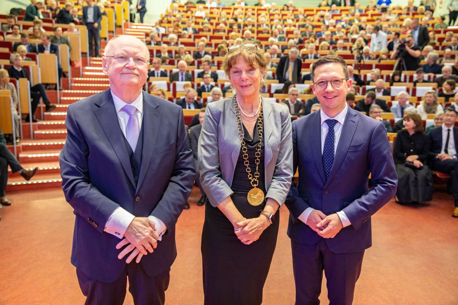 Denise Hilfiker-Kleiner in der Mitte mit Professor Manns und Falko Mohrs bei der Amtskettenübergabe im Hörsaal F